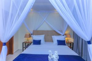 a bedroom with a bed with blue and white curtains at Bon Bini Residence Apart-Hotel - Pool, Fast WiFi, Security, Backup Power in Kampala +24 photos