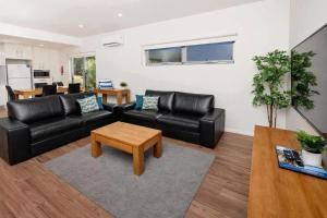 a living room with a black leather couch and a table at BIG4 Emu Beach Holiday Park in Albany