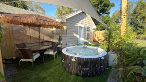 a hot tub in a yard with a table and an umbrella at Tropical Casita LaVida in Tampa