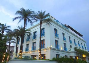 a white building with palm trees in front of it at The Promenade in Pondicherry
