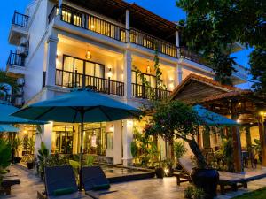an exterior view of a building with umbrellas at The Quin Riverside Villa in Hoi An