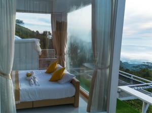 a bedroom with a bed and a large window at ชาเลต์ ภูทับเบิก in Ban Maeo Thap Boek