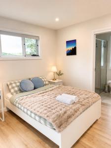 a white bedroom with a large bed with blue pillows at Cosy Granny flat in Epping in Epping