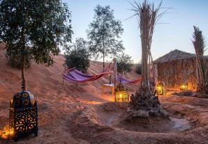 a desert area with a hammock and a tree at Ali & Sara's Desert Palace in Merzouga