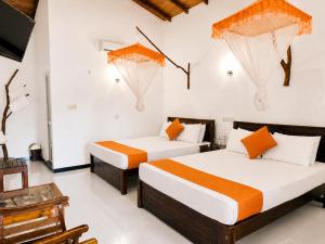 two beds in a room with white walls at Rainbow Safari & Lodge in Udawalawe