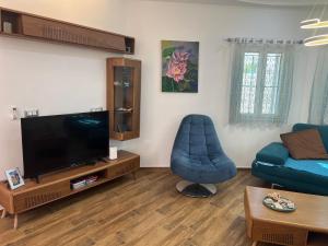a living room with a television and a blue chair at villa baya midoun in Midoun