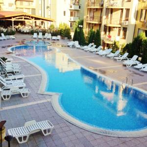 a large swimming pool with white lounge chairs in a hotel at Siana 1 Apartment in Sveti Vlas