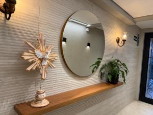 a mirror on a wall with a plant on a shelf at Suíte Boutique 302 Cheia de Graça in Divinópolis