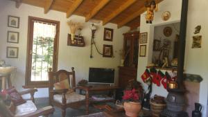 a living room with a tv and a couch and a chair at Alpina Hostería in Villa Gesell