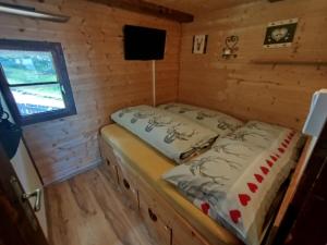 a bed in a wooden cabin with a window at Almhütte Andrea in Wildschönau