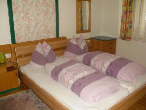 Una cama con almohadas moradas y blancas. en Nagelehof, en Ainet