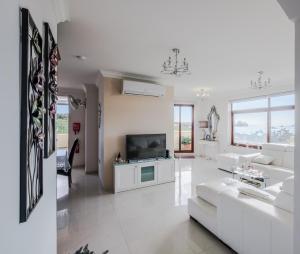 a living room with white furniture and a tv at Seagull Penthouse Marsaxlokk in Marsaxlokk