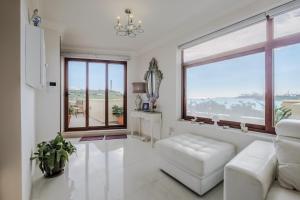 een woonkamer met een witte bank en een groot raam bij Seagull Penthouse Marsaxlokk in Marsaxlokk