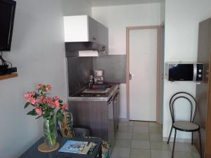 a small kitchen with a table with a vase of flowers at L'insulaire Studios in Saint-Denis-dʼOléron