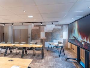 a conference room with tables and chairs and a large screen at Novotel SPA Rennes Centre Gare in Rennes +103 photos