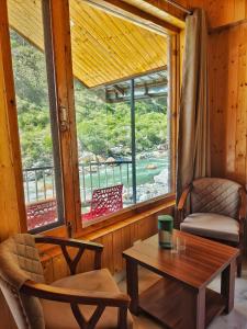 a room with a table and chairs and a window at Riverside Bliss Cottages in Gushaini