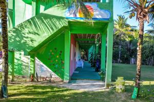 a green building with a doorway with a palm tree at Pousada Sol Nascente in Cumuruxatiba