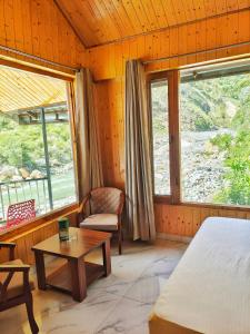 a bedroom with a bed and a table and windows at Riverside Bliss Cottages in Gushaini