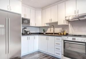a white kitchen with white cabinets and appliances at Messila in Gatineau