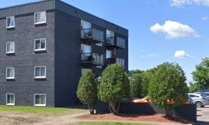 a black building with trees in front of it at Messila in Gatineau