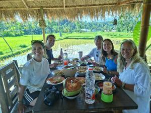 a group of people sitting at a table with food at padi bungalow in Tetebatu