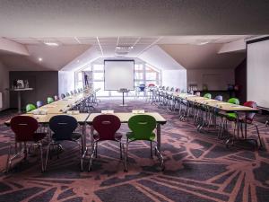 a large room with tables and chairs and a screen at ibis Styles Brive Ouest in Brive-la-Gaillarde