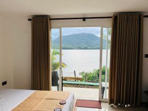 a bedroom with a view of the water at Elee Villa - Waterfront Retreat with Victoria Reservoir & Mountain Views in Teldeniya