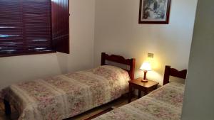 1 dormitorio con 2 camas, lámpara y ventana en Pousada Casa Grande, en Iguape