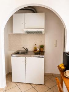 a kitchen with white cabinets and a sink at Meltemi Apartments in Elafonisos