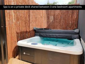 a jacuzzi tub sitting next to a wooden wall at A Stones Throw From Town A-Frame in Dunedin