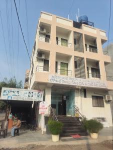 a building with a man sitting in front of it at Hotel Sai Neelam in Shirdi