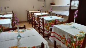 a room with tables and chairs with flowers on them at Pousada Casa Grande in Iguape