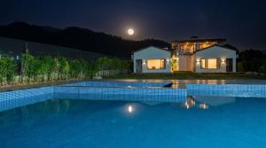 a house with a swimming pool at night at Corbett Retreat in Rāmnagar