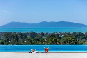 a drink next to a swimming pool with mountains in the background at Rockstarvillas Grande Siesta in Nathon Bay +28 photos