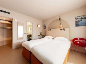 a bedroom with a large bed and a red chair at ibis Styles Marseille Centre Prado Place Castellane in Marseille