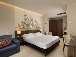 a bedroom with a bed and a blue couch at Mercure Rimini Lungomare in Rimini