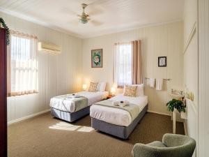 ein Hotelzimmer mit zwei Betten und einem Stuhl in der Unterkunft Maleny Hotel in Maleny