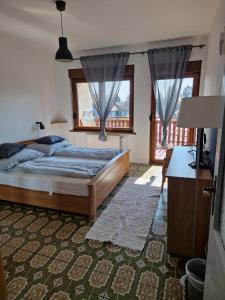 a bedroom with a bed and a desk and windows at Réhelyi in Szigliget