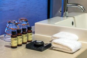 a bathroom counter with four bottles of essential oils and towels at Pullman Bangkok King Power in Bangkok