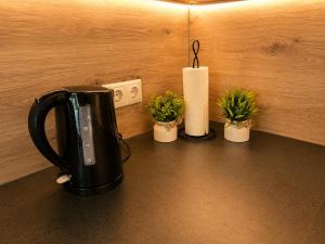 a black tea kettle and four potted plants on a counter at Schongau Suites Premium Apartments M in Schongau +6 photos