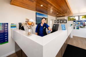 a woman is standing behind a white counter with flowers at BIG4 Emu Beach Holiday Park in Albany +108 photos
