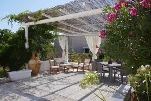 a patio with tables and chairs under a pergola at Trullo La chicca della valle in Cisternino