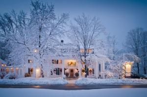 uma casa branca com árvores e luzes cobertas de neve em The Dorset Inn em Dorset