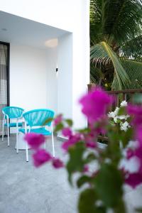 two blue chairs and a table and purple flowers at Rasgrand in Rasdhoo