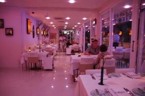 ein Restaurant mit weißen Tischen und Menschen, die darauf sitzen in der Unterkunft Devamli Hotel in Marmaris