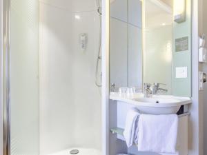 a white bathroom with a sink and a shower at ibis budget Basel City in Basel +46 photos