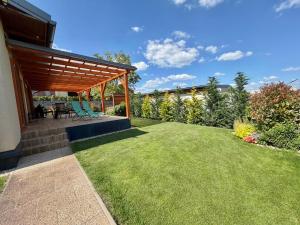 a backyard with a wooden pergola and a lawn at Chata VeloVino in Moča