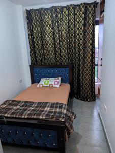 a small bedroom with a bed and a curtain at Alchemist Homes in Kiambu