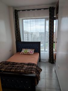 a bedroom with a bed and a large window at Alchemist Homes in Kiambu