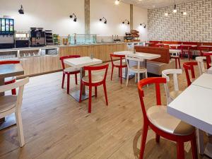 a restaurant with white tables and red chairs at ibis Styles Amsterdam City in Amsterdam